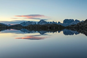 Red Sky Prints: Blue sky and pink clouds reflected in Lago Nero at dawn