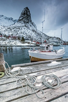 Reine Prints: A boat moored in the cold sea in the background the snowy peaks, Reine. Lofoten Islands