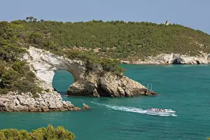 Natural Arch Prints: Boat passing under Arco di San Felice arch with Torre Gattarella behind