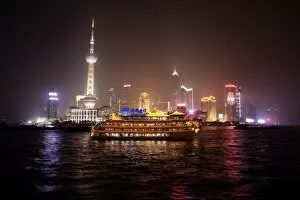 Images Dated 6th November 2009: Boat set against Shanghai illuminated skyline, Shanghai, China, Asia