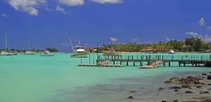 Docked Prints: Boats docked in the clear waters of Grand Baie in Mauritius with blue skies and palm trees in the background
