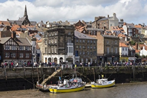 Boats moored on the West Side of the River Esk, with many passers-by on Pier Road