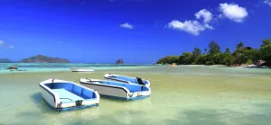 Traditions Prints: Boats rest on the clear water of Anse Source dArgent beach at La Digue during a sunny day in Seychelles