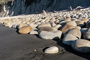 Zealand Prints: Boulder field along a black sand beach with cliffs in West Coast New Zealand showcasing unique geological features