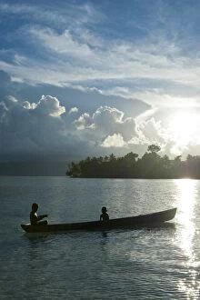 Boys in a canoe in backlit in the Marovo Lagoon, Solomon Islands, Pacific