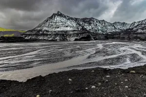 Glacial Prints: Braided glacial rivers flow through volcanic landscape beneath stormy skies in Iceland