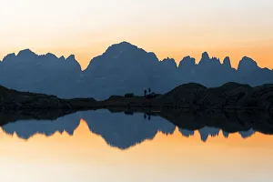 Silhouetted Gallery: Brenta Dolomites mountains reflected in pristine water of Lago Nero di Cornisello at