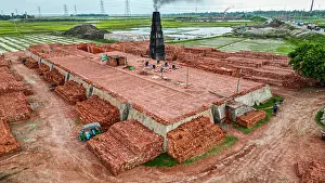 Economy Prints: Brick manufacturing process at a factory with stacks of bricks ready for use in Dhaka