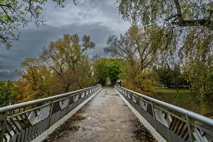 Season Prints: Bridge in Gomel park offers a view of trees and sky in autumn with grey clouds overhead in Gomel