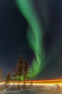 Glow Prints: Bright lights from a Jeep illuminate the landscape while the Aurora Borealis dances in the night sky above Great Slave