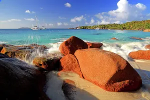 Sailboats Prints: Bright water splashes at rocks along the shore near sailboats on a tropical beach in Seychelles