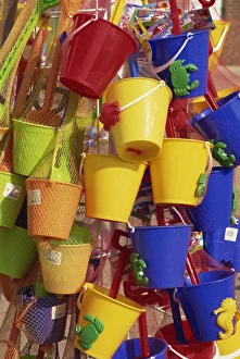 Fifteen brightly coloured buckets, mainly yellow and blue, for sale, Skegness
