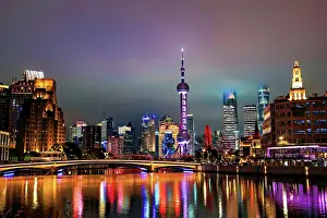 Bustling Prints: Brightly lit skyline of Lujiazui at night covered in mist viewed from Suzhou Creek in Shanghai
