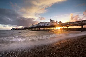 Typically English Gallery: Brighton Pier at sunset with dramatic sky and waves washing up the beach, Brighton