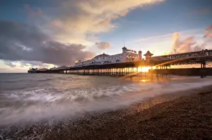 Glowing Prints: Brighton Pier at sunset with dramatic sky and waves washing up the beach, Brighton