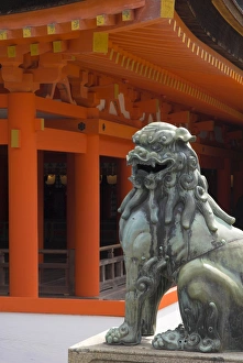 Shinto Prints: Bronze lion with traditional orange wooden roof beyond