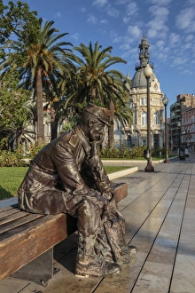Bronze statue of a sailor on a wooden bench with palm trees, Town Hall backdrop, Cartagena
