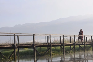 Images Dated 26th December 2007: Buddhist monk, walking in the early morning on a wooden walkway, Inle Lake