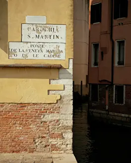 Neighborhood Prints: Detail of building with sign in Venice showing connection to local history and culture in Veneto