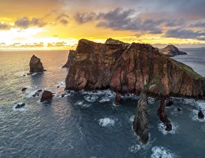 Burning sky at dawn on cliffs washed by ocean, Ponta do Rosto viewpoint