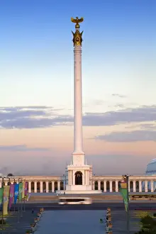 Astana Prints: Bus passing KazakYeli monument (Kazakh Country) at dusk