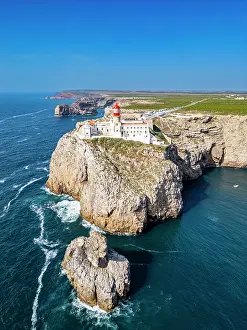 Bright Prints: Cabo de Sao Vicente lighthouse stands on a cliff by the Atlantic Ocean in Sagres Algarve Portugal with clear skies