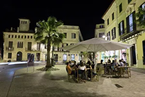 Eating And Drinking Prints: Cafe scene at night in the old town, Placa del Princep, Mahon, Menorca, Balearic Islands