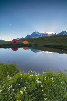 Graian Alps Prints: Camping tents in the green meadows surrounded by flowers and alpine lake, Mont De La Saxe