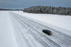 Lapland Prints: Car traveling on ice track on a frozen lake in the snow covered landscape