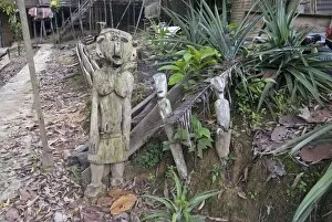 Carved spirits of men and a woman standing at the entrance to Iban tribal longhouse at Ngemah beach on the Lemanak