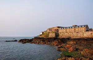 Guernsey Prints: Castle Cornet Fortress stands on a rocky islet in the sea near Saint Peter Port in Guernsey Channel Islands at sunset