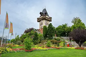 Clock Prints: Castle Hill hosts Clock Tower with gardens and visitors in Graz during a cloudy day in Austria