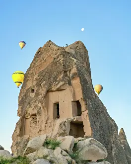 Cappadocia Prints: Cave inside rock formation in Cappadocia with hot air balloons during sunrise in Turkey