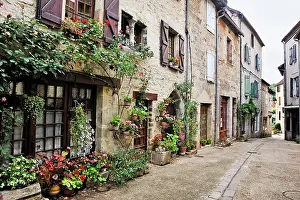 Front Prints: Charming street in Cajarc with flower pots and stone houses in a quiet setting of southwest France