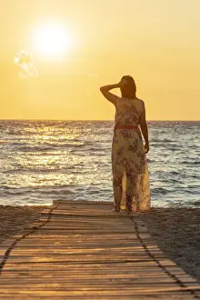 40 44 Years Prints: Charming woman contemplating the sea at sunset standing on Matala beach, Crete