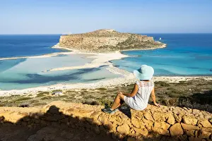 40 44 Years Prints: Charming woman with sundress and hat contemplating the crystal turquoise sea and lagoon