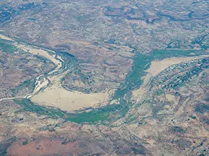 Ecosystems Prints: Charter flight view of a river winding through mountains in Madagascar showcasing the landscape
