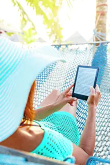 Hammock Prints: Cheerful woman on a hammock enjoying reading a digital book on tablet
