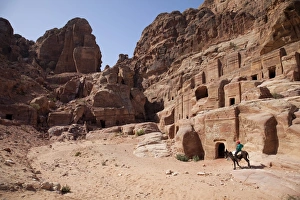 Donkey Prints: Child riding a donkey in front of cave dwellings in Petra
