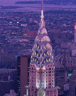 Aerials Prints: The top of the Chrysler Building illuminated in the evening with a bridge