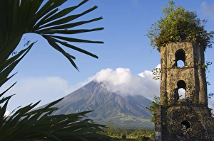 Church belfry ruins and volcanic cone with smoke plume of Mount Mayon Church belfry ruins and volcanic cone with smoke plume of Mount Mayon
