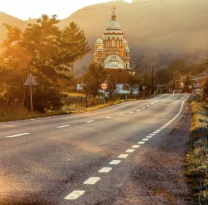 Romania Prints: Church and road bathed in golden light during the golden hour in Romania's landscape