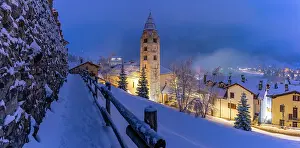 Snowfall Prints: Church of Saint Pantalon and snow covered town centre and mountainous background in winter at dusk