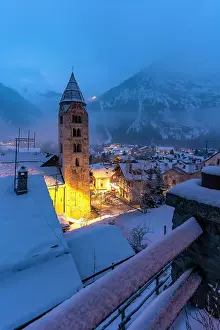 Alpinism Prints: Church of Saint Pantalon and snow covered town centre and mountainous background in winter at dusk