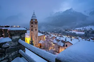 Cozy Prints: Church of Saint Pantalon, snow covered town centre and mountainous background in winter at dusk