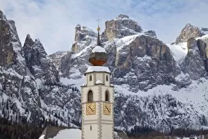 The church and village of Colfosco in Badia, 1645m, and Sella Massif range of mountains under winter snow, Dolomites