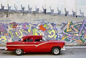 Images Dated 31st March 2009: Classic red American car parked in front of grafitti covered wall, Havana
