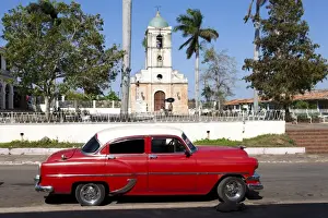 The Caribbean Prints: Classic red American car parked by the old square in Vinales village, Pinar del Rio