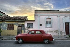 Images Dated 28th March 2009: Classic red American car parked outside houses at sunset, Cienfuegos, Cuba