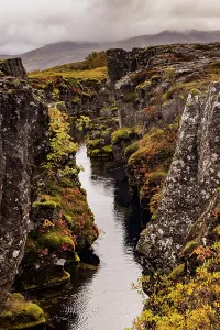 Thingvellir Prints: Clear blue water flows through volcanic rock in Silfra fissure at Thingvellir National Park in autumn